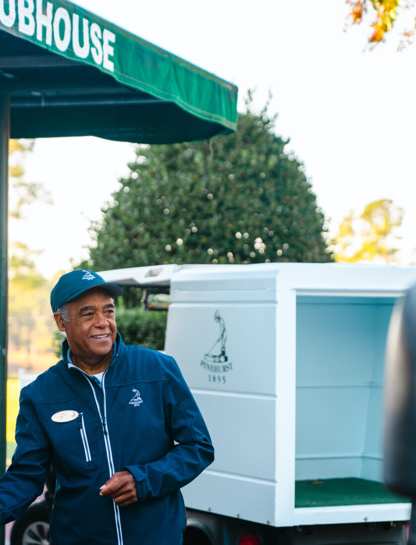 A man stands smiling under a golf tent