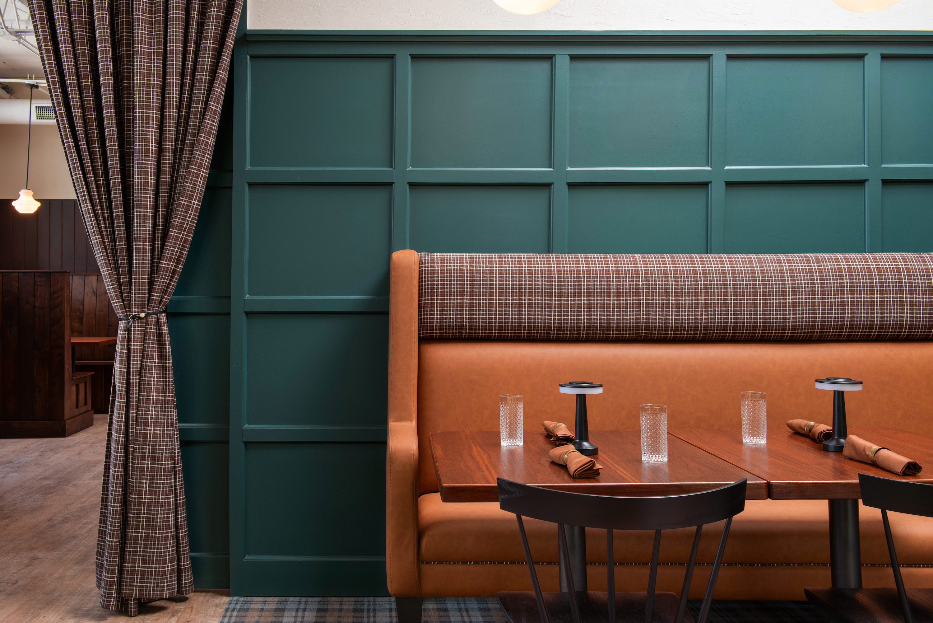 A leather booth framed by dark green paint details and a set table