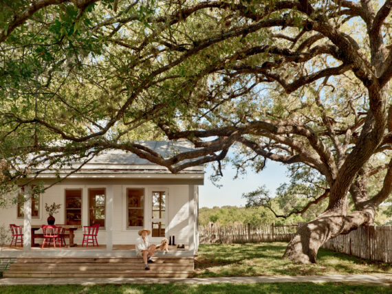 A man and dog sit on a porch of a house