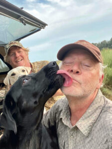 David DiBenedetto and T. Edward Nickens with two dogs, one of which is licking Nickens
