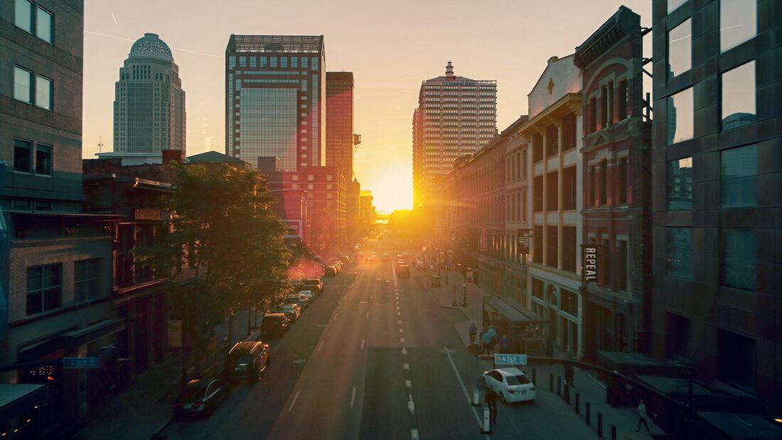 a cityscape with the sun rising over the road