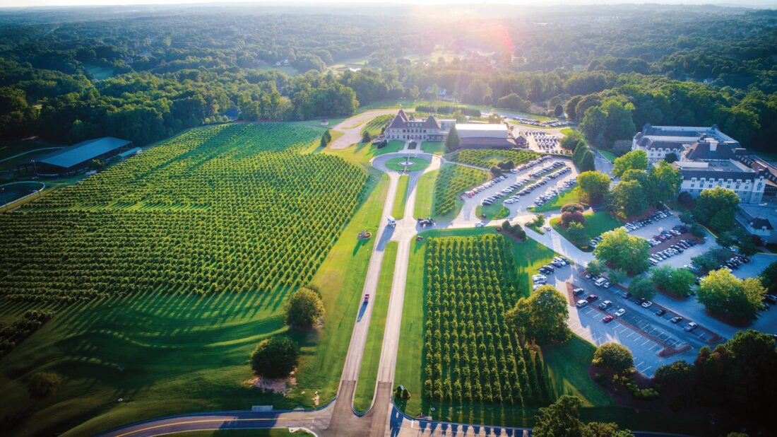 aerial shot of an estate with a long driveway and parking lot filled with cars