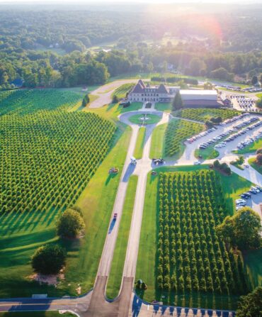 aerial shot of an estate with a long driveway and parking lot filled with cars