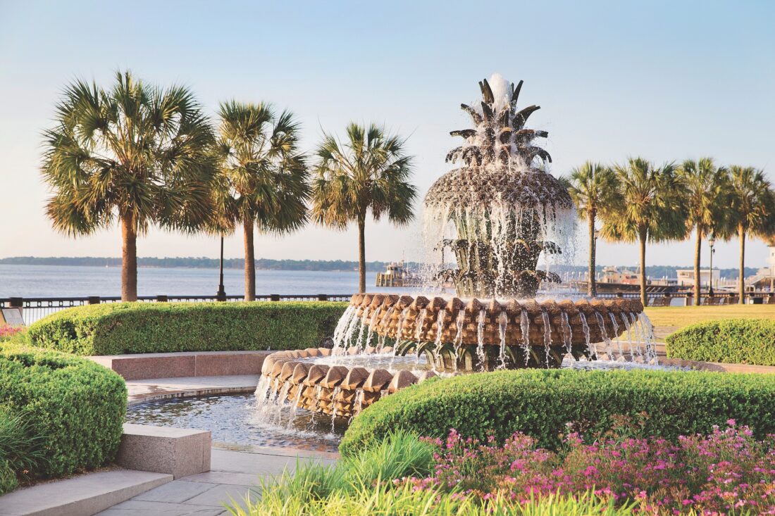 a fountain with a pineapple on top next to a harbor with palmetto trees