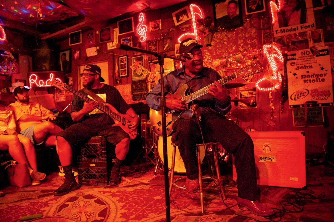 a musician plays guitar on a red lit stage