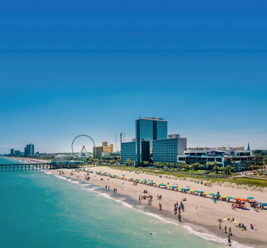 a shoreline with sky scrapers and a ferris wheel on the beach