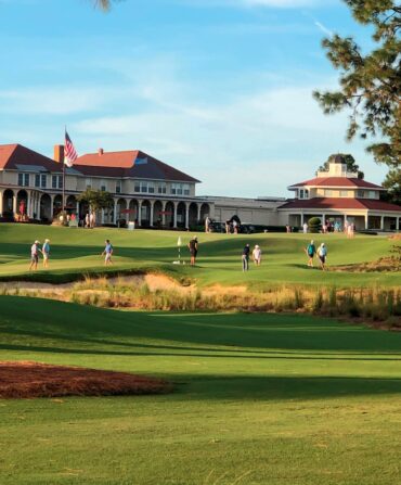 a golf course with a building with a red roof in the background