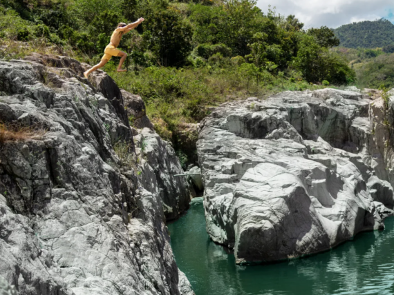 A person jumping into water from a rock