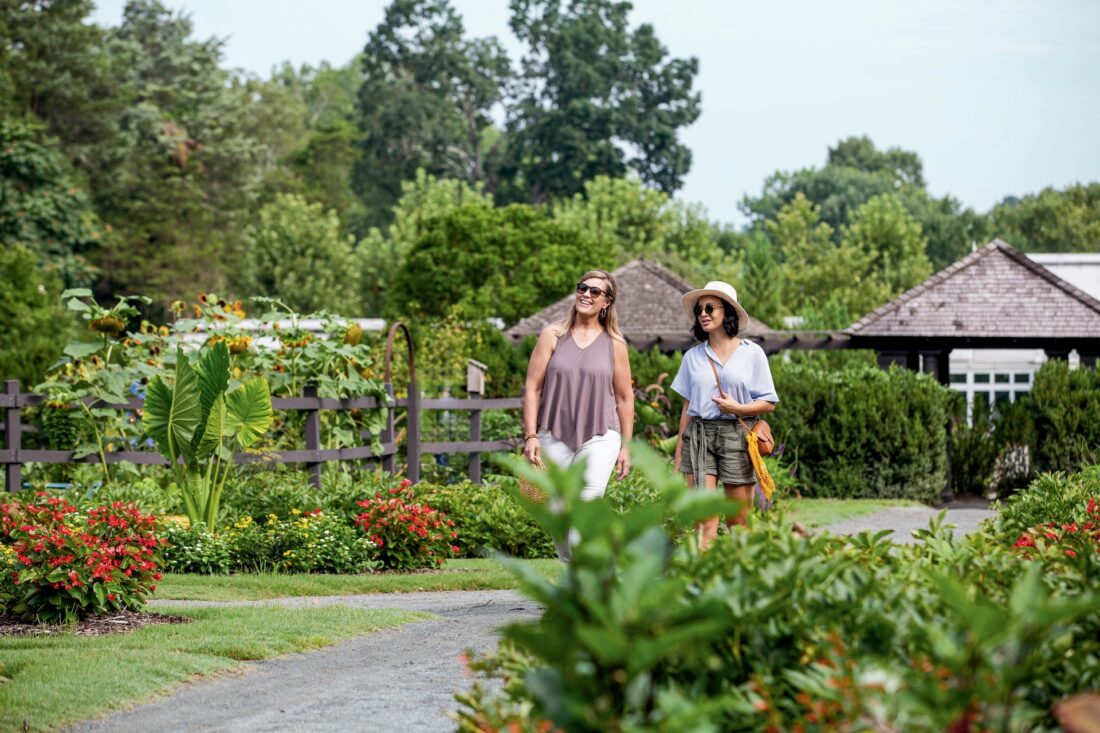 two women walking through a garden