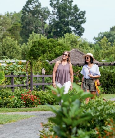 two women walking through a garden