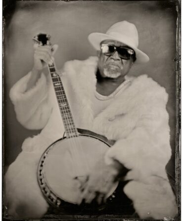 A black and white photo of a man with a banjo