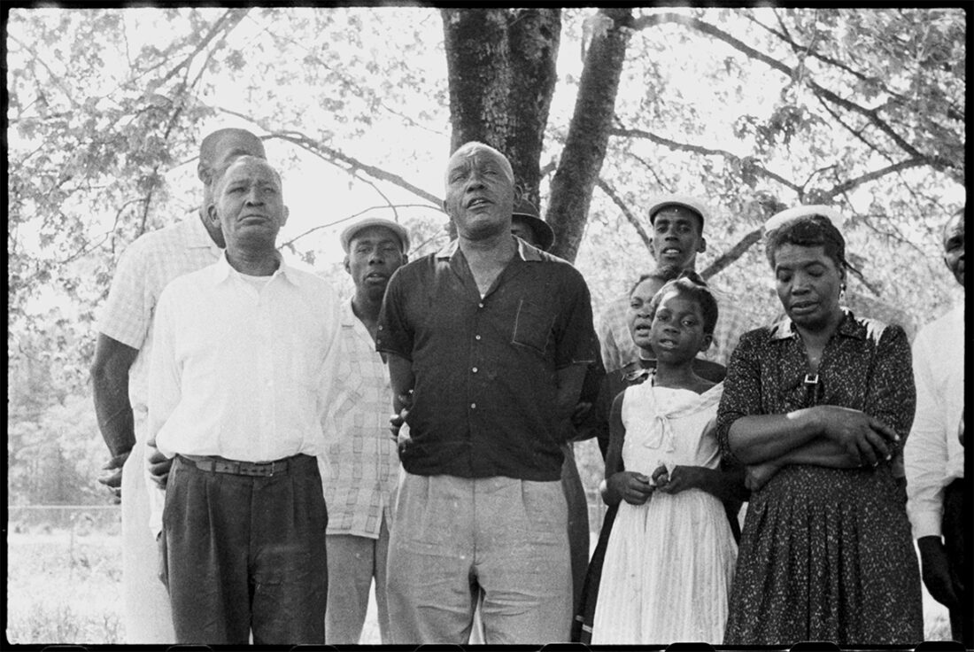A group of people sing under a tree