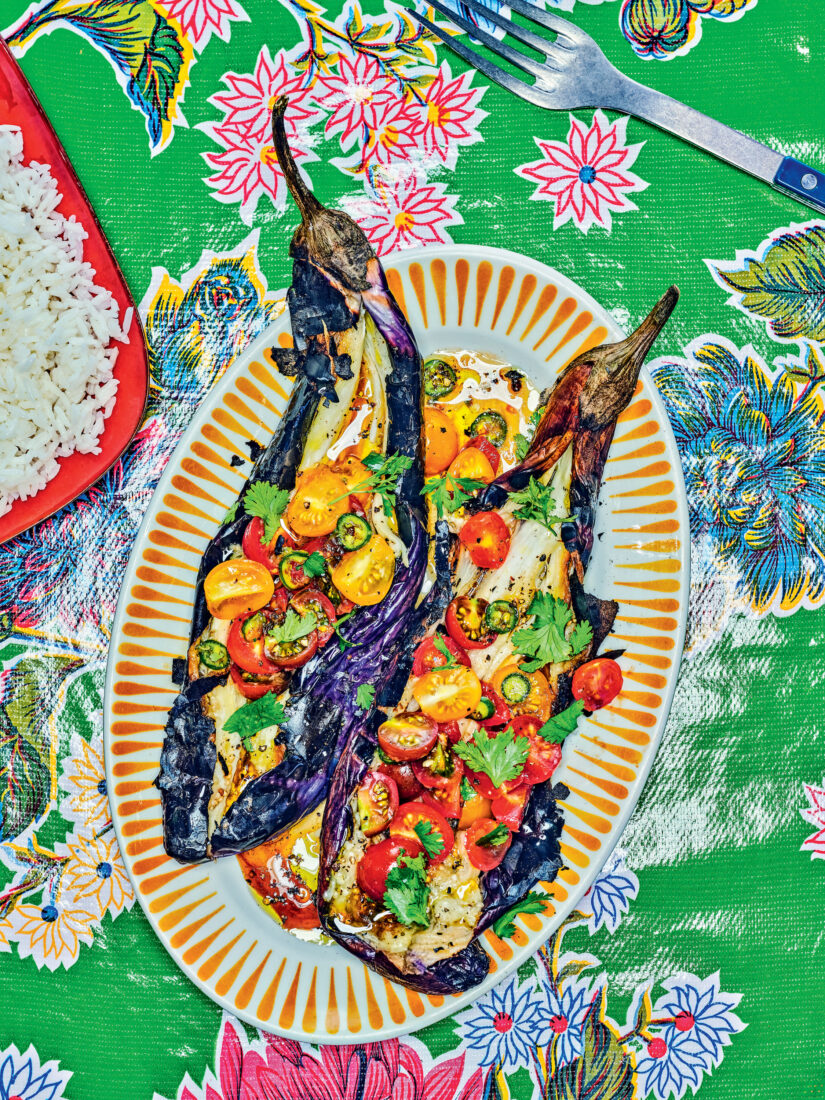 An eggplant and tomato dish on a green patterened tablecloth