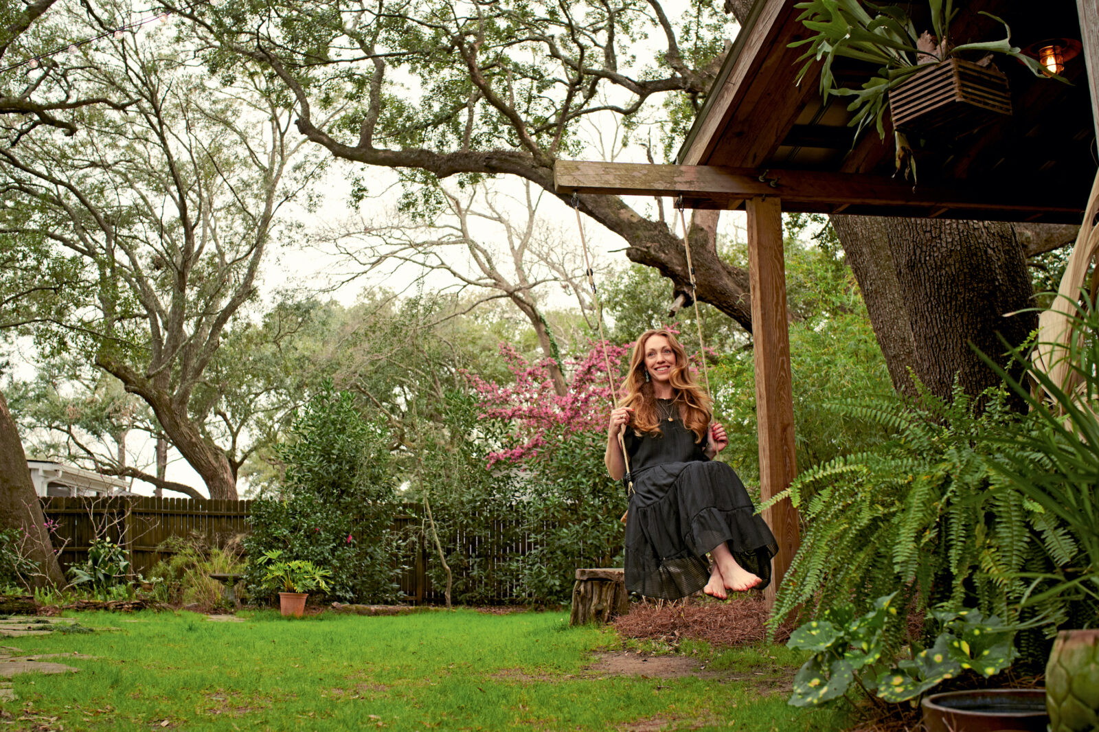 A woman swings on a swing in her garden