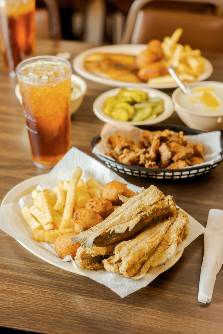 Fried catfish, gator tail, and all the fixings on a black basket tray on a table