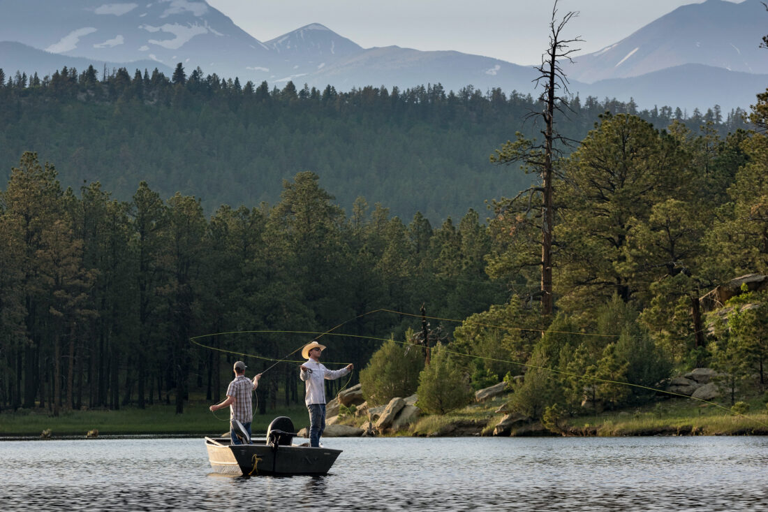 A man fly fishes from a boat