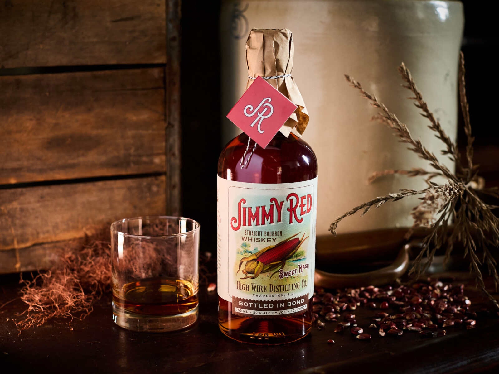 A bottle of bourbon with a partly filled glass on a table