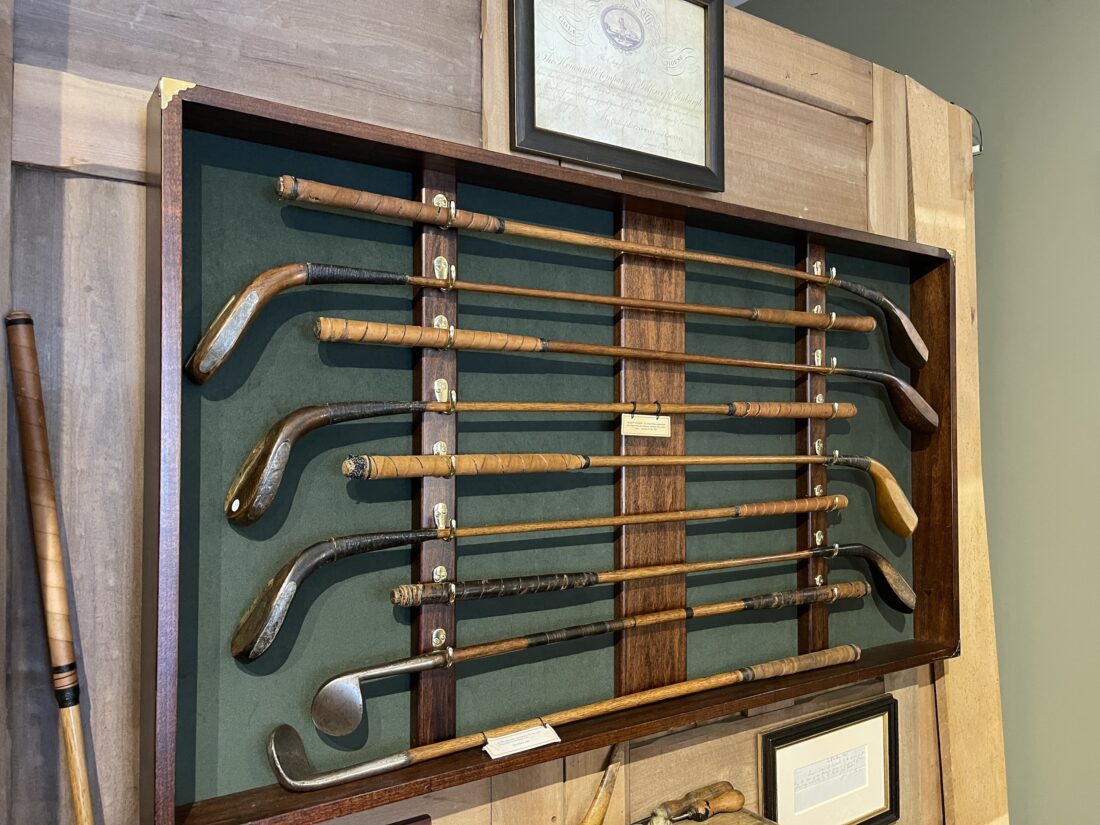 Old, wooden golf clubs on display.