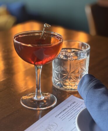A floral Manhattan sits on a wooden table.