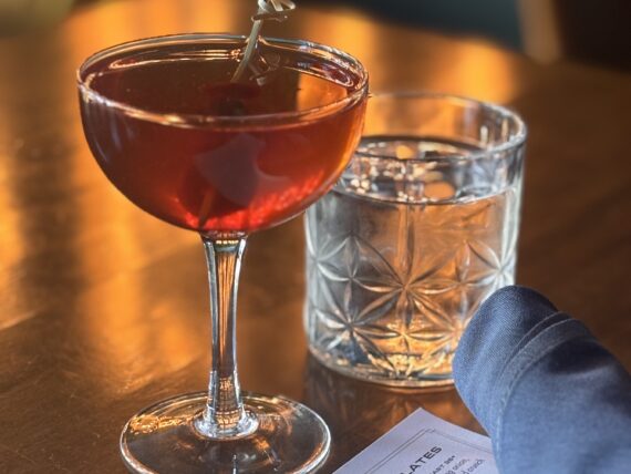 A floral Manhattan sits on a wooden table.