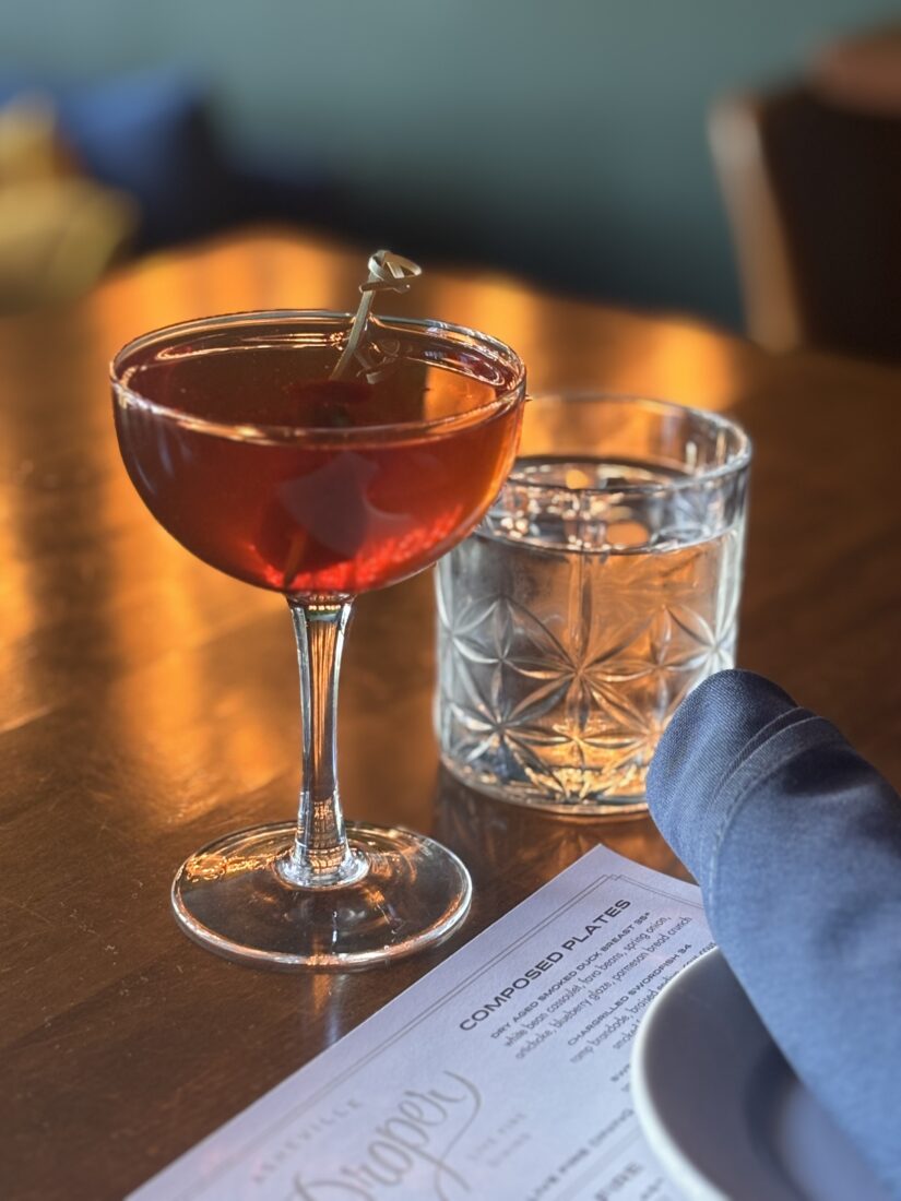 A floral Manhattan sits on a wooden table.