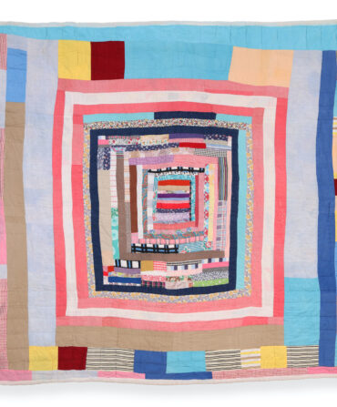 A housetop quilt with blue, pink, white, yellow, and red fabric