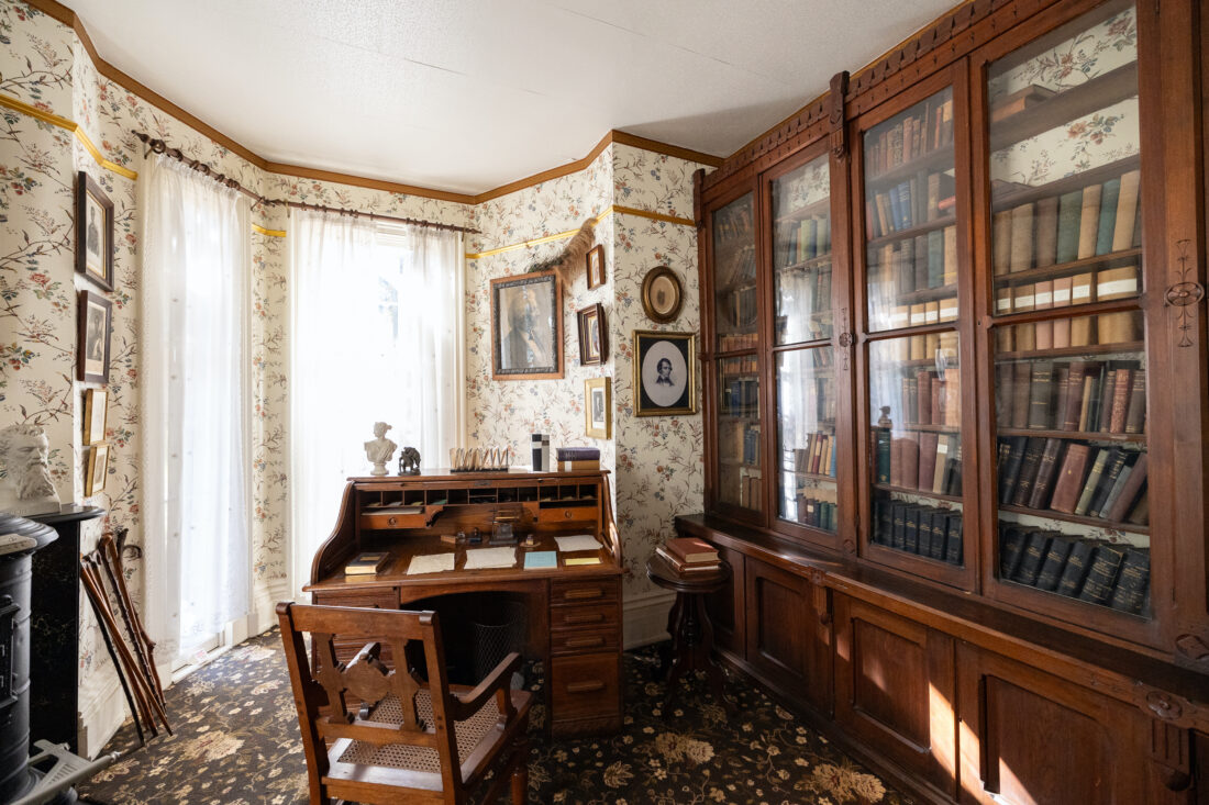 An old home study with floral wallpaper and dark wood furniture