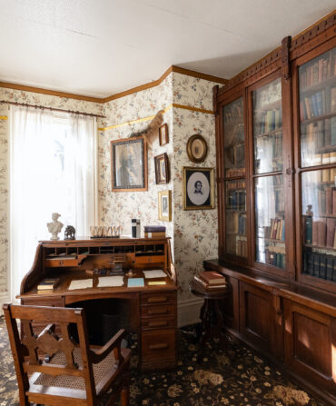 An old home study with floral wallpaper and dark wood furniture