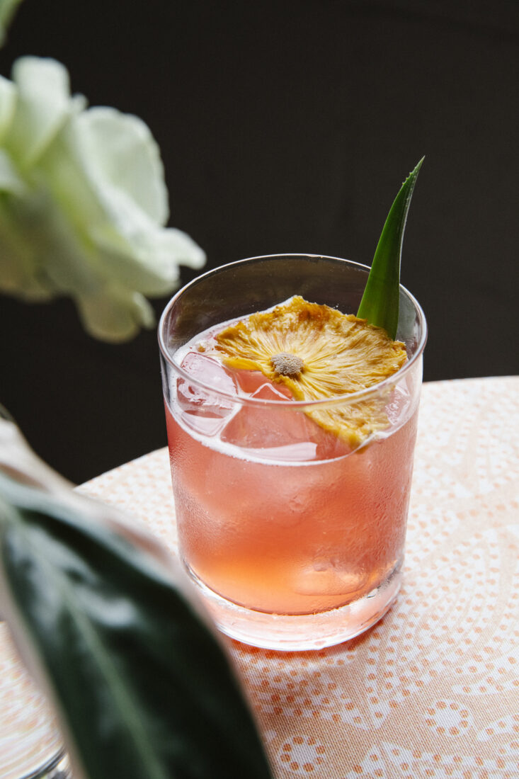 a cocktail with a flower garnish on a table