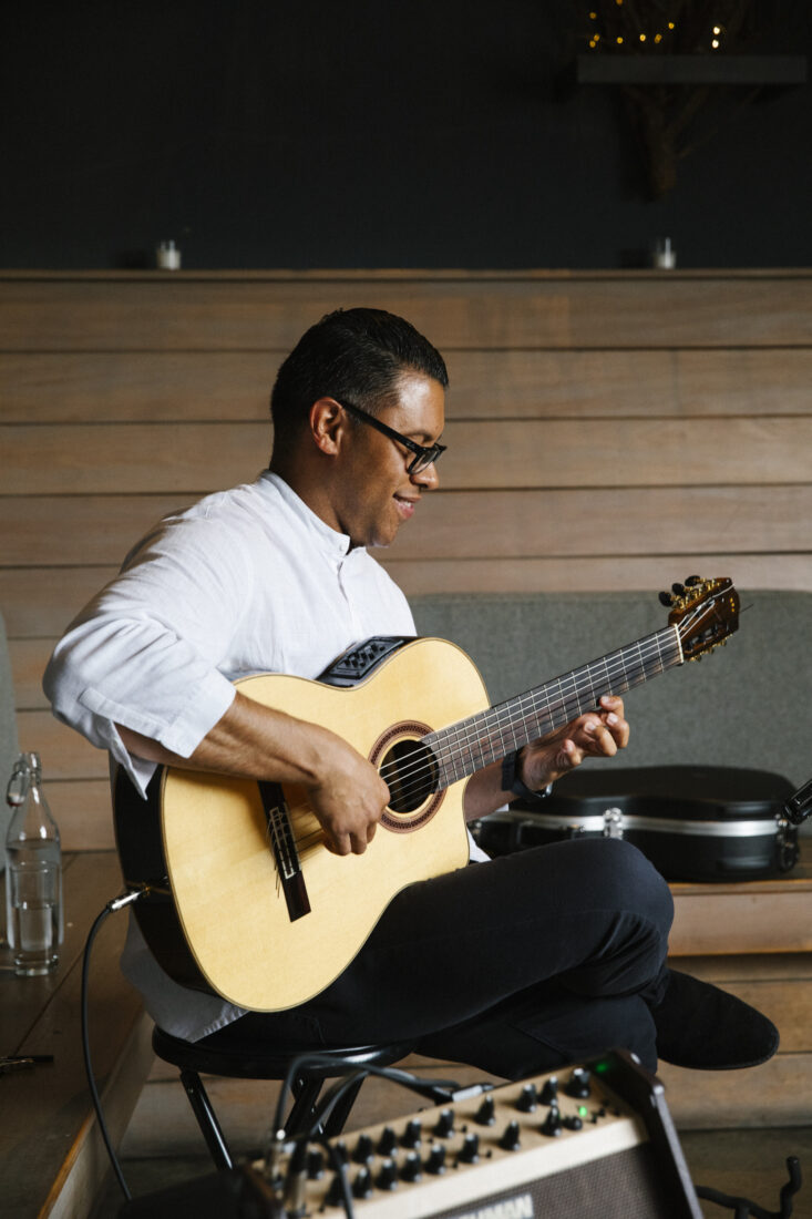 a man sitting and playing guitar