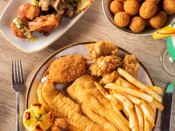 three plates of fried food on a table with silverware