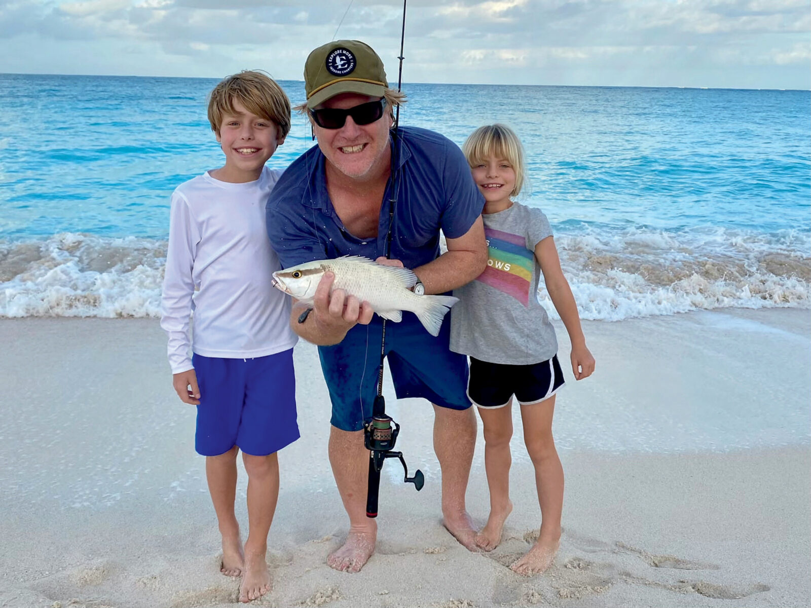 A man with two kids pose with a fish