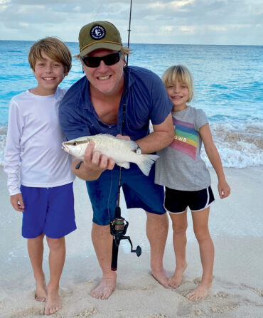 A man with two kids pose with a fish