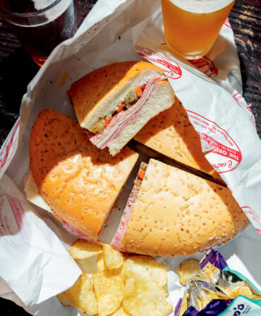 A muffuletta in a basket with chips