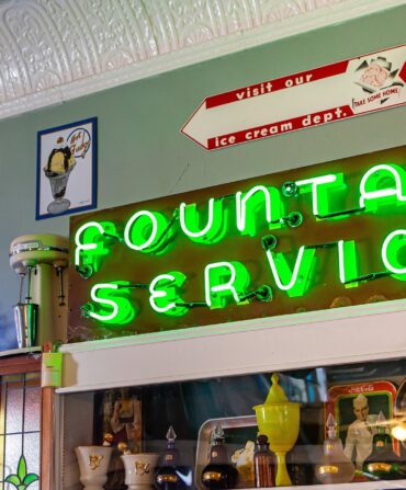 A neon sign inside of Mike's on Main reads "Fountain Service."