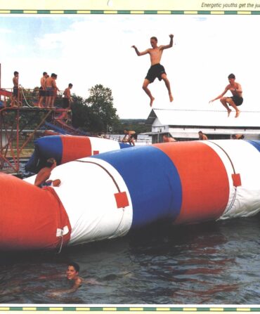 A red white and blue Blob on the water. Kids jump on it and swim around it