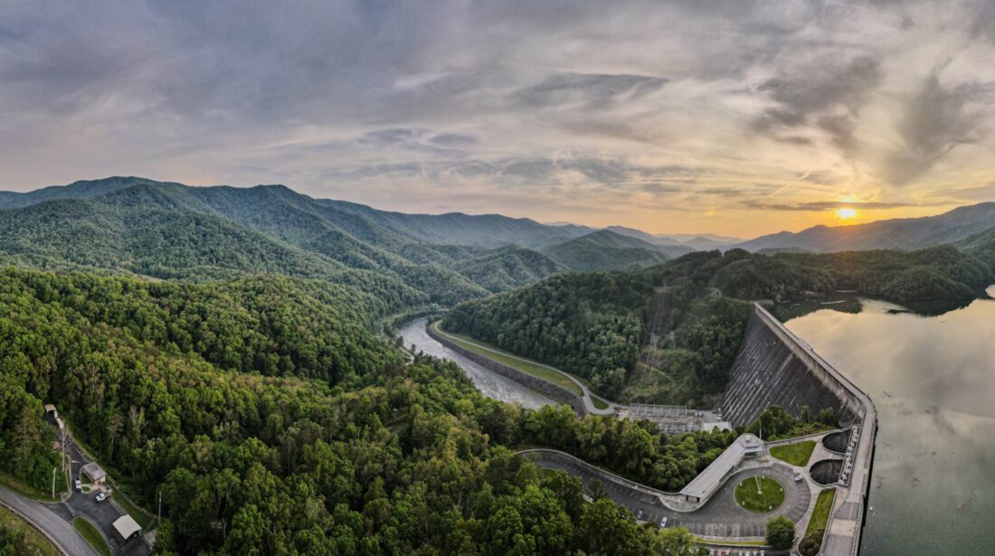 An aerial shot of the mountains and a lake with a winding road