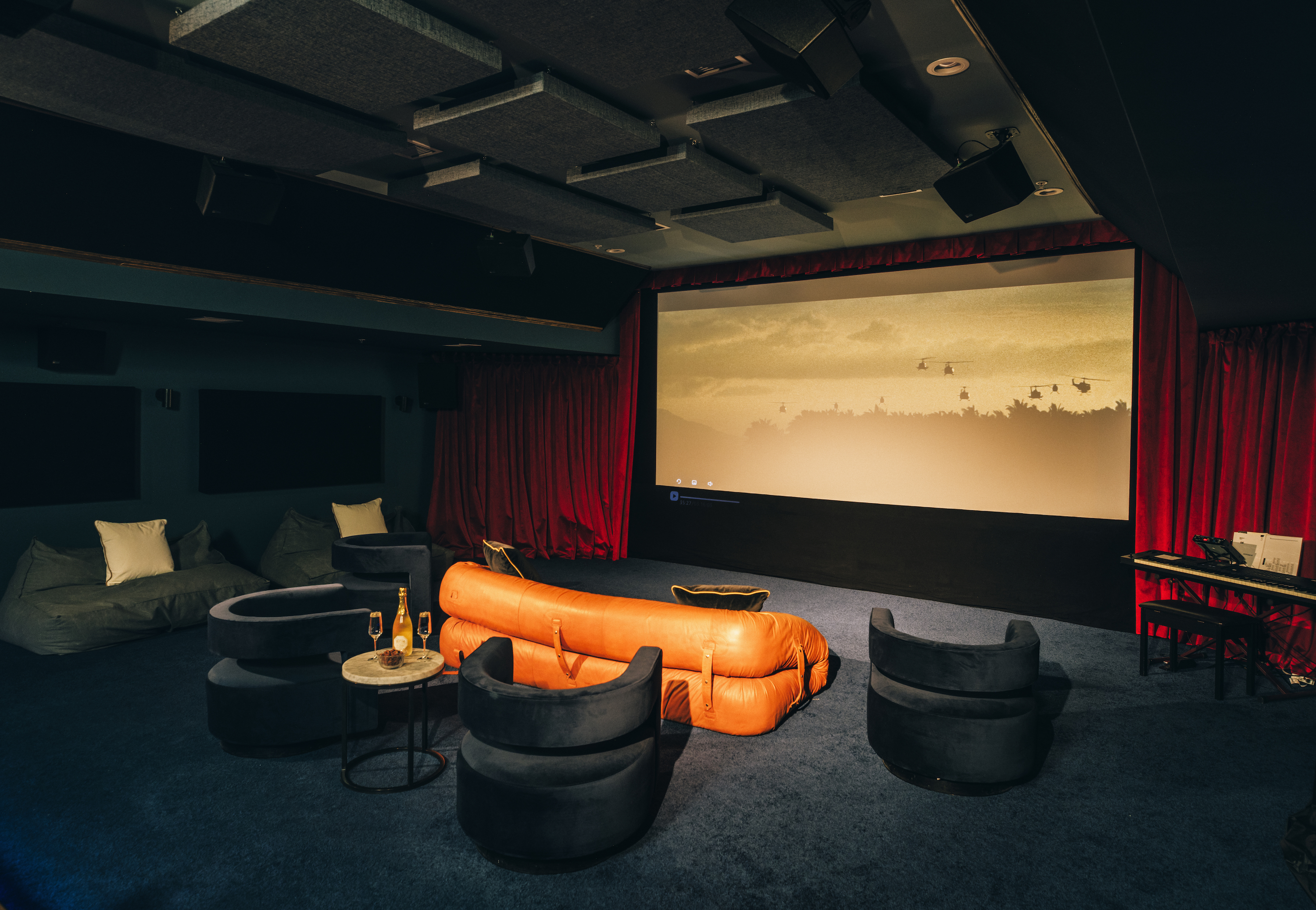 A refined, dark movie room with an orange sofa