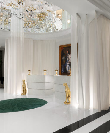 A white hotel lobby with a black bronze horse sculpture, crystal chandelier, and renaissance painting