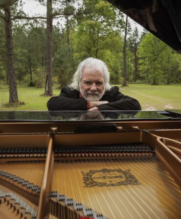 Chuck Leavell leans over his piano on his land