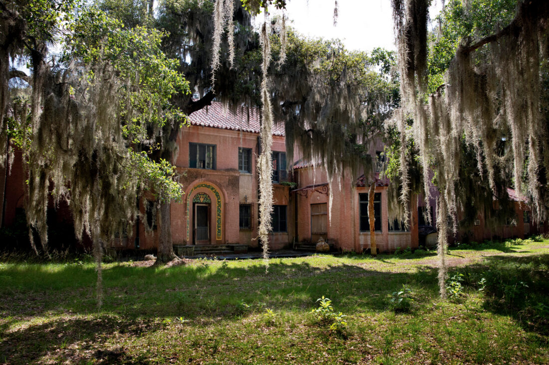 A revival mansion with trees draped in spanish moss