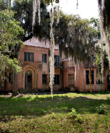 A revival mansion with trees draped in spanish moss