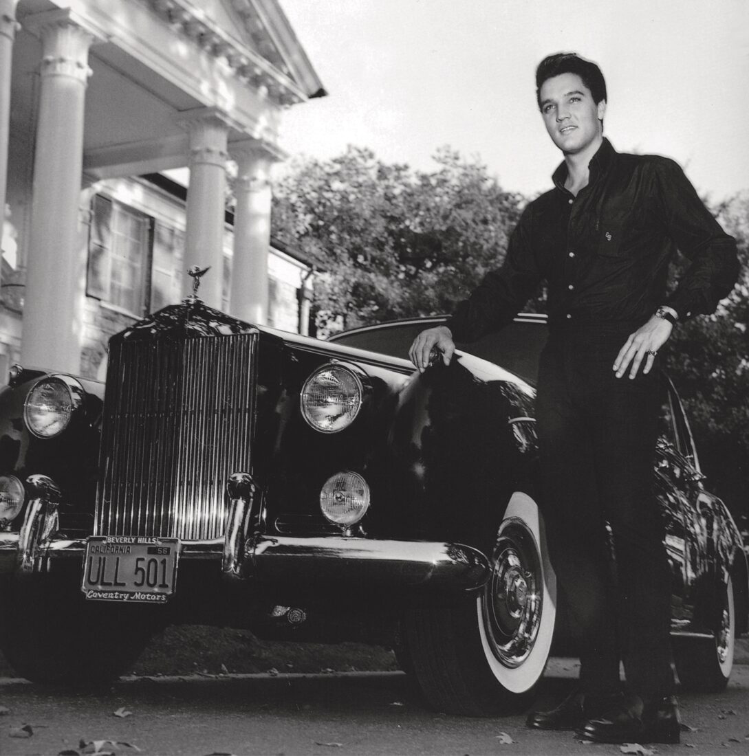 Elvis stands by an old car at Graceland