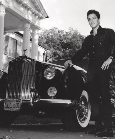 Elvis stands by an old car at Graceland