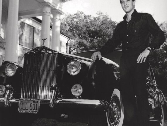 Elvis stands by an old car at Graceland