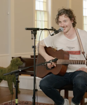 A man sits with a guitar