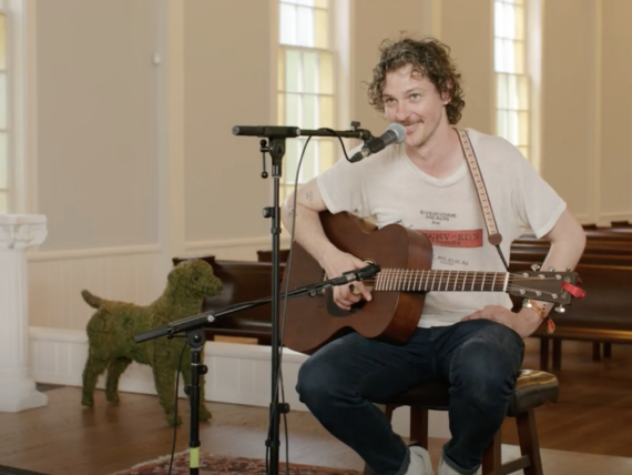 A man sits with a guitar