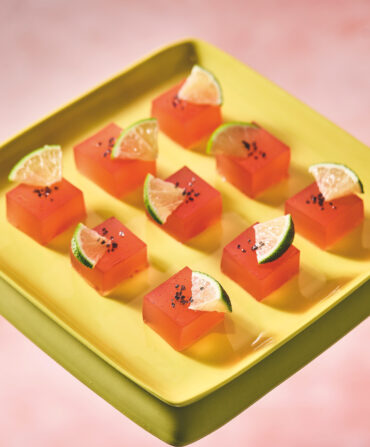 A platter of jello squares with slices of lime