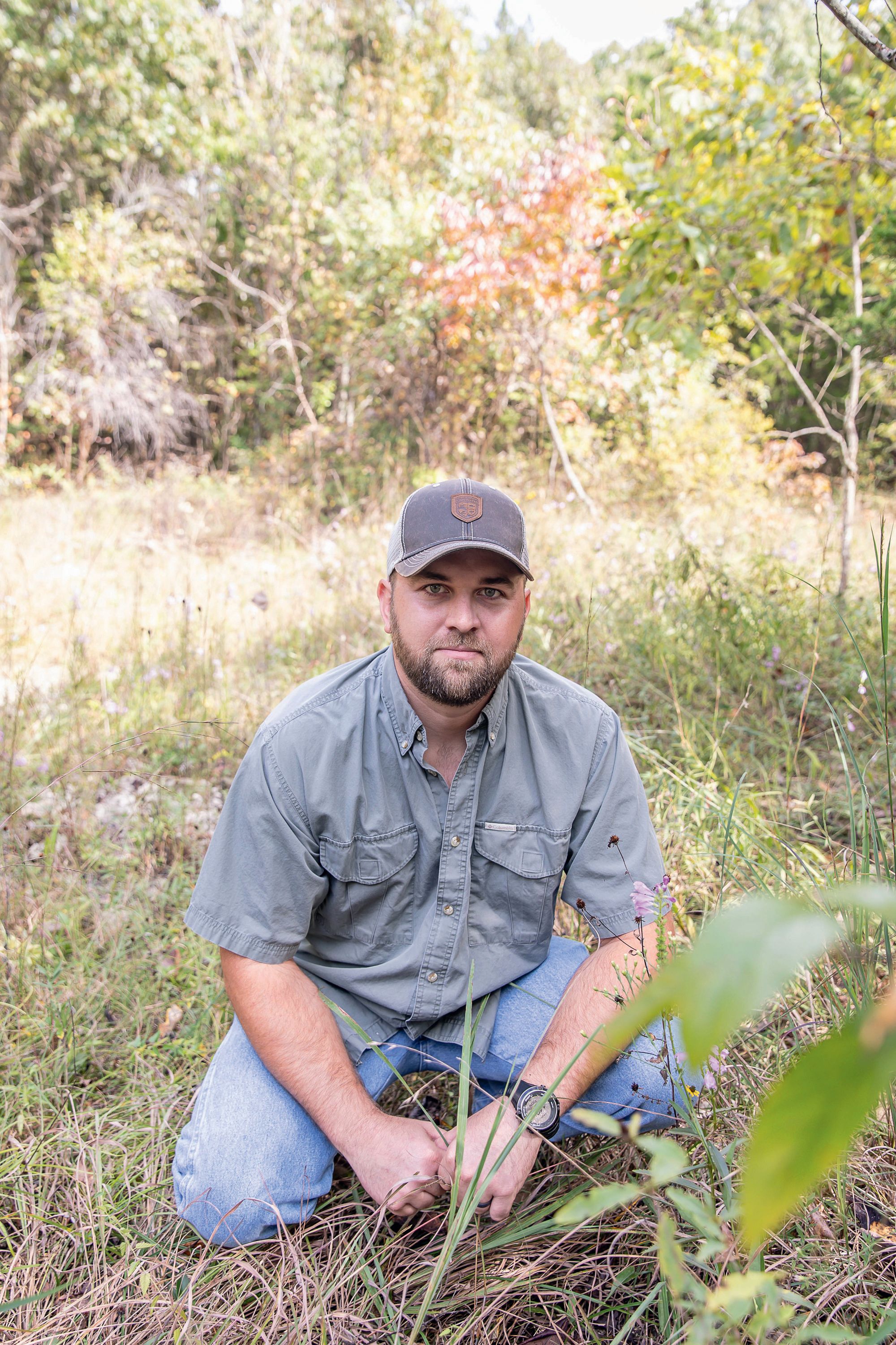 A man crouches in grasses