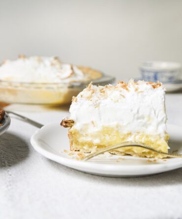 A slice of coconut cream pie with meringue on top.